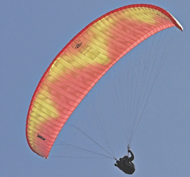 the man is flying on a parachute against the blue sky