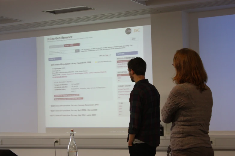 two people are watching a presentation on the screen