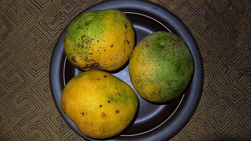three mangoes and two pears in a bowl
