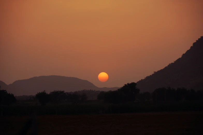 a red sunset in front of the mountains and hills