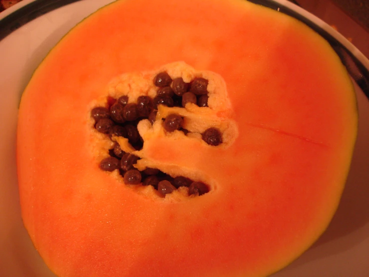 a papaya slice with a couple pieces cut off and raisins arranged in the center