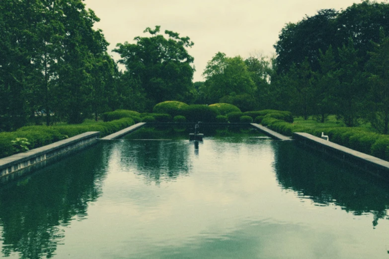 a garden pond in front of a green lawn and fence