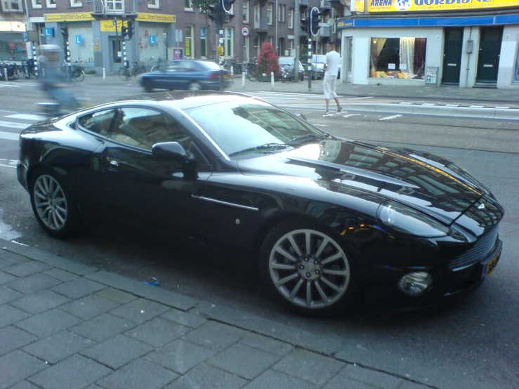 a very nice looking black sports car parked by the street