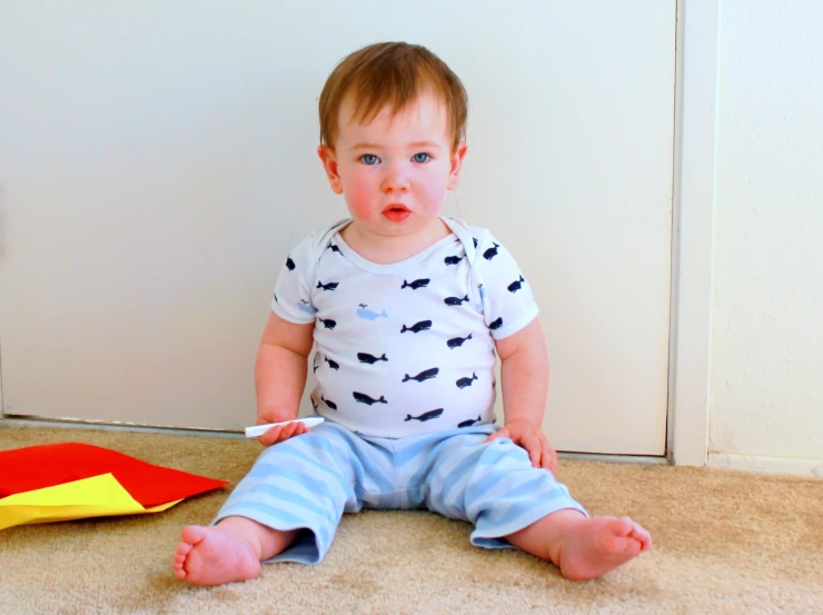 a small baby sitting on the ground near a wall