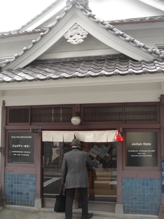 the man in the gray coat is standing outside the building