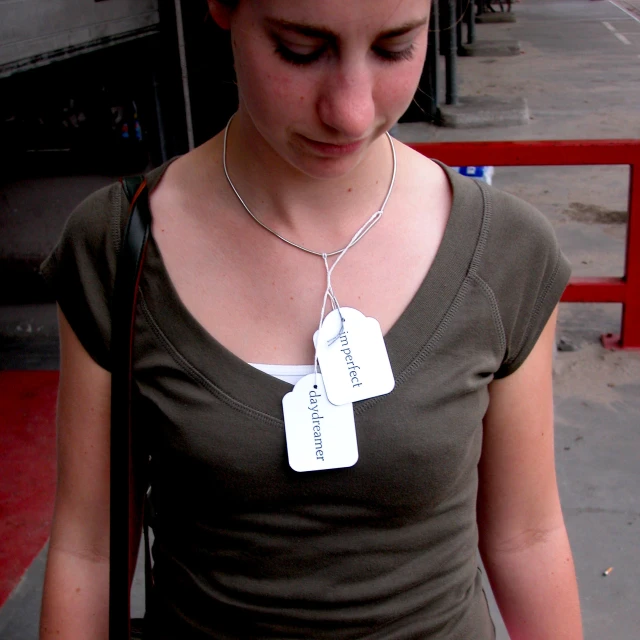 the woman is wearing two tags attached to a necklace