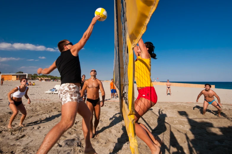 people on the beach playing volley ball on a sunny day