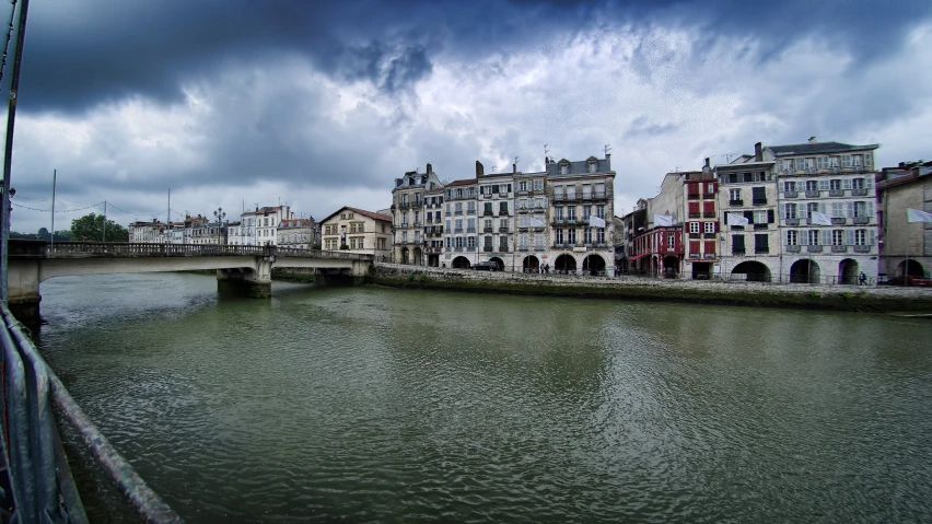 a picture of a very cloudy sky over buildings on the river