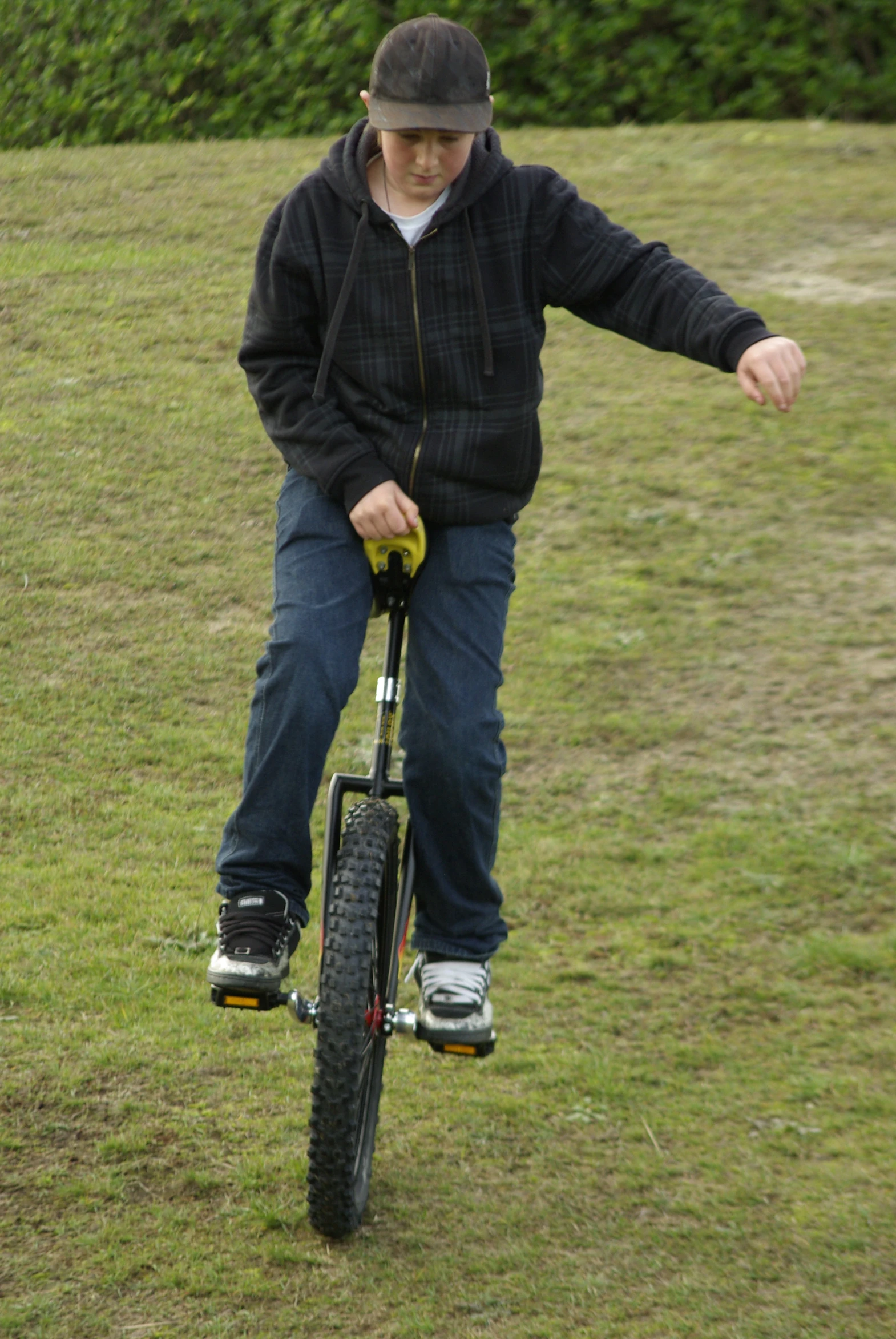 a boy in a black jacket is riding a bicycle