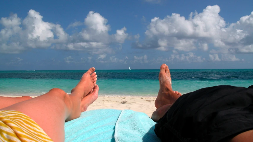 a person lays on their stomach as they are enjoying the sand and blue water