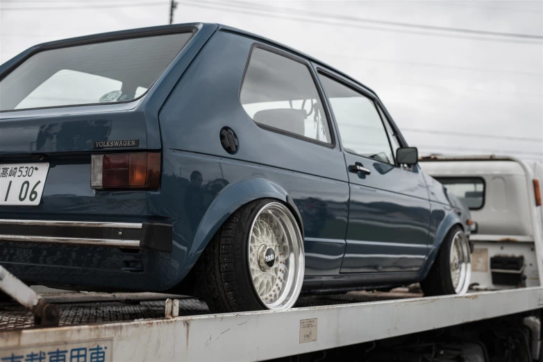 a large truck with a small blue car on the back