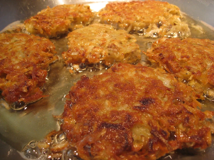 four patties of food frying on an oven grill