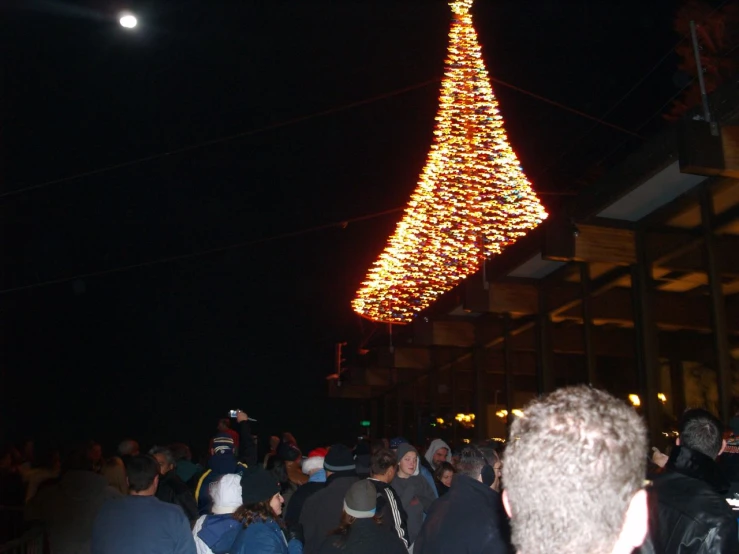 a large group of people gathered around a large lighted christmas tree