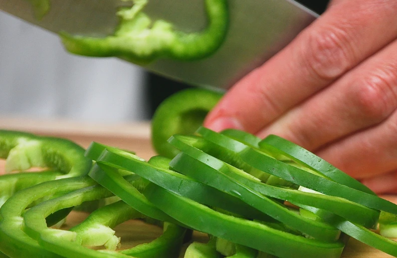 person slicing a vegetable with a knife on a  board