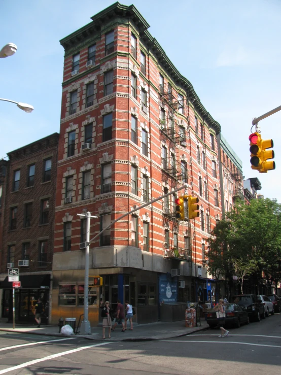 people walking in front of an apartment building at the corner of a street