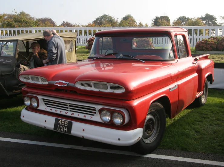 a red truck parked on a field next to a park