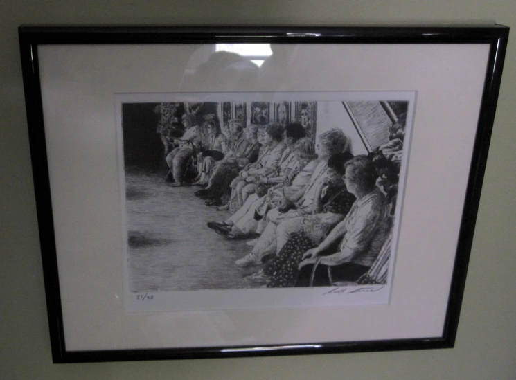 framed image with black border displaying several people and one of them on the wall