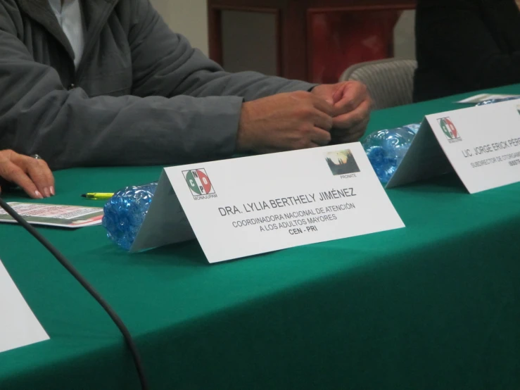 two people sit at a table with their hands resting on some papers