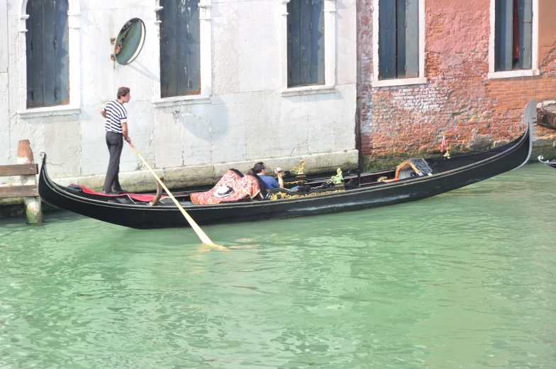 a woman stands next to a man who is in a boat