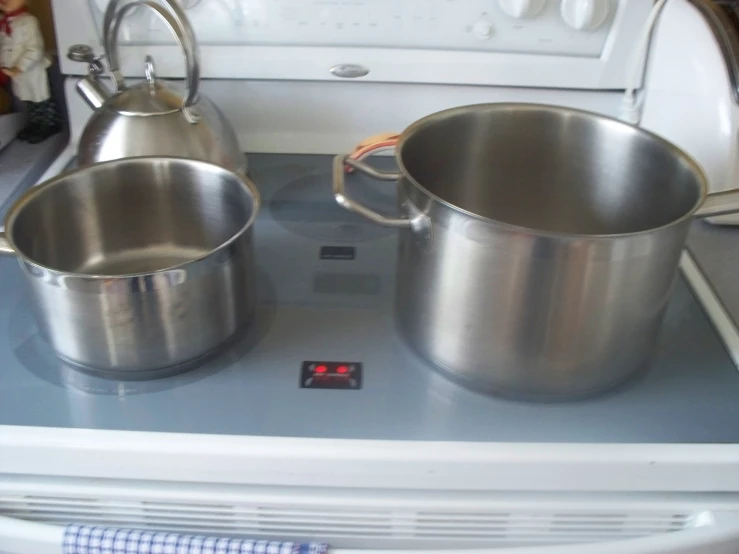 two sauce pans sit on top of an electric stove
