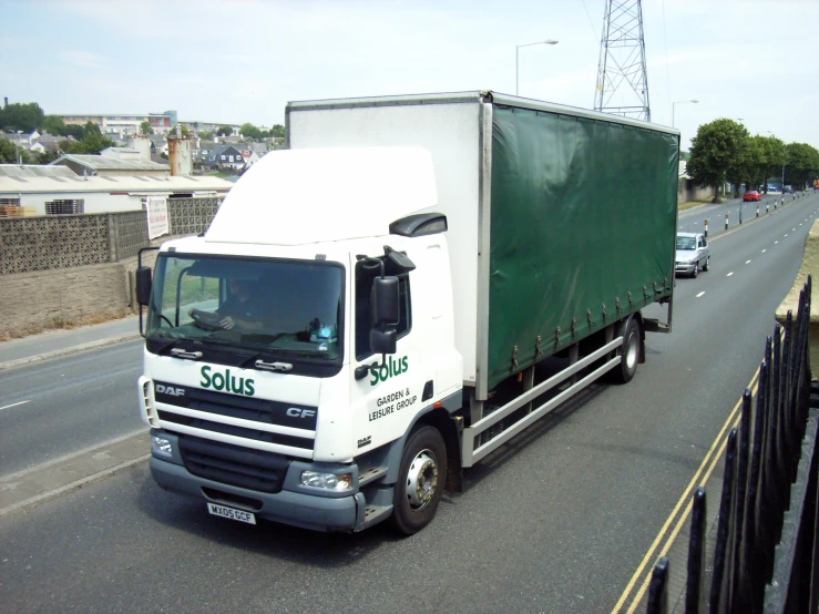 a white truck is carrying a green trailer