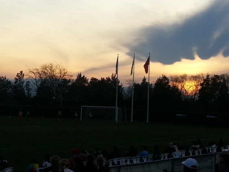 the sun is rising behind clouds on a soccer field