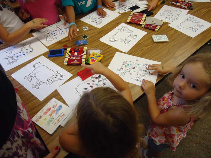 three little girls at a table making drawings