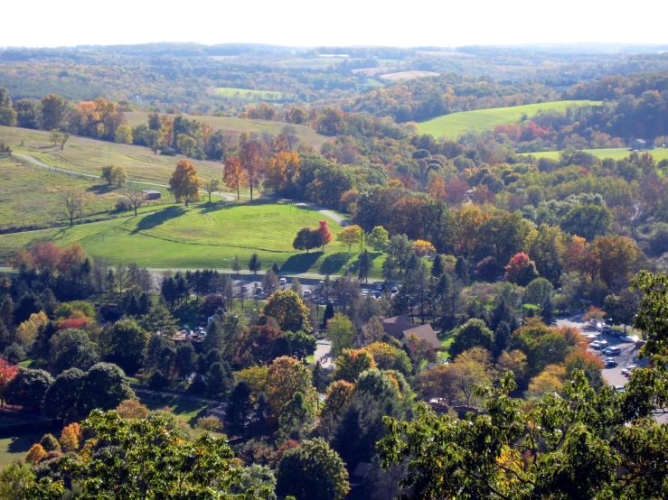 a view of a valley and trees with some yellow, orange, red and green leaves