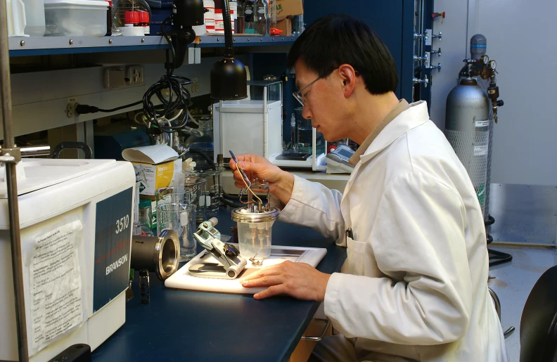 a male lab technician in a white lab coat working on a device