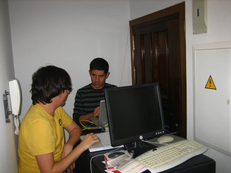 two men sitting in front of computer monitors