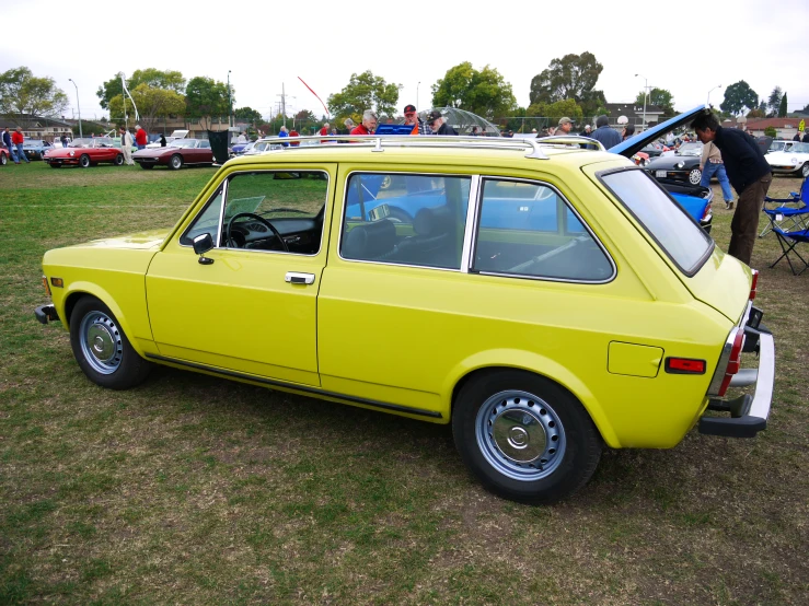 an old yellow car sitting on the grass