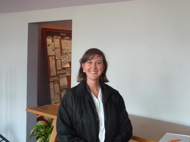 a woman smiling and standing in front of a wooden table