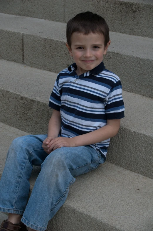 a little boy sitting on steps with his feet up