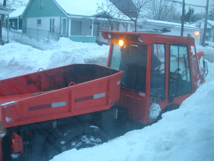 a red truck driving down a snow covered road