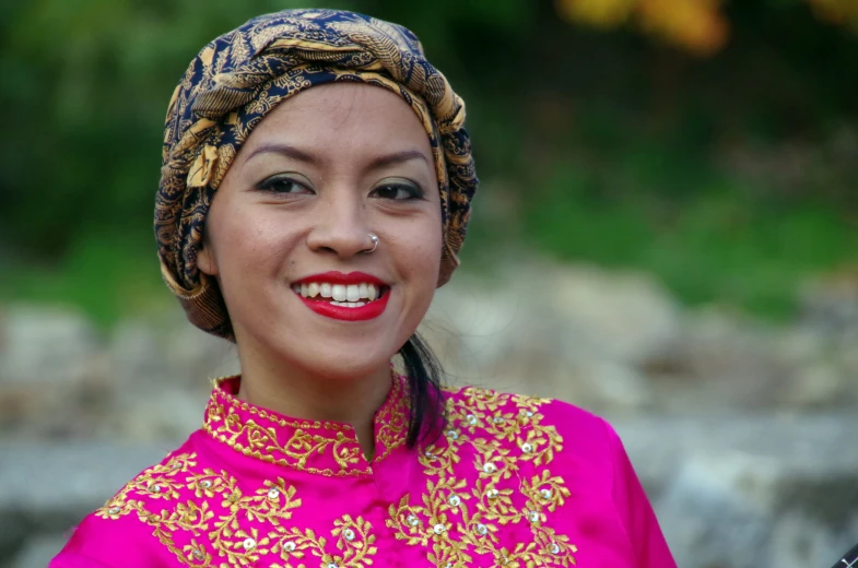 a smiling woman in a dress with a bandana on her head