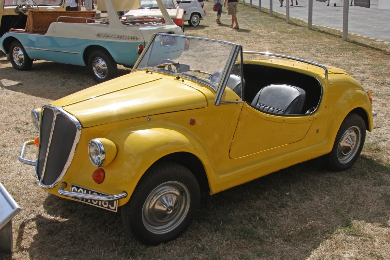 the antique yellow sports car is parked in a lot