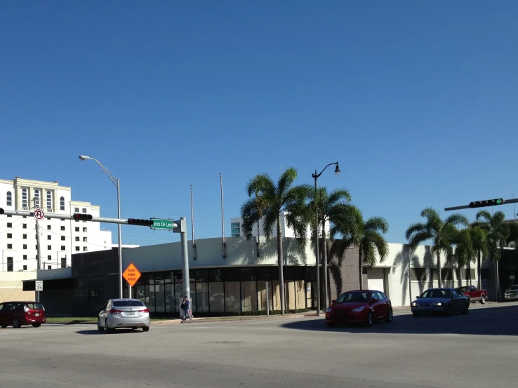 many cars drive on a city street near a large building