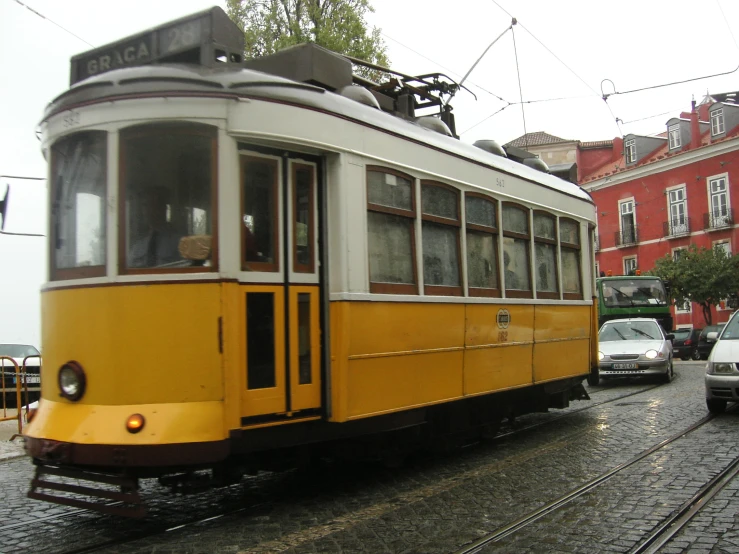 a small yellow train traveling through a town on a cloudy day