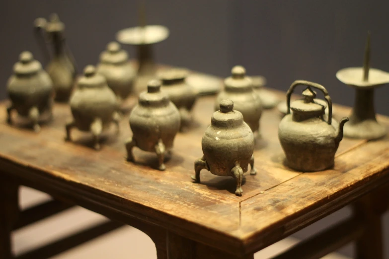 old tea pots sitting on wooden table with various holders on each side