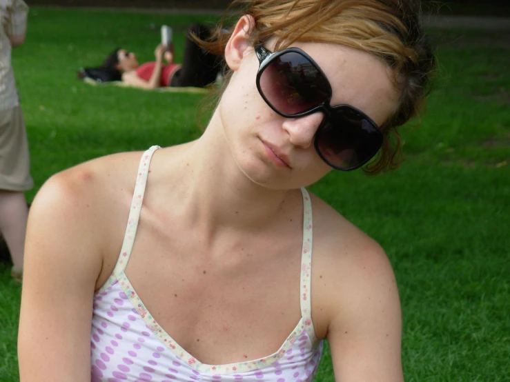 a woman in sunglasses sitting on grass and resting