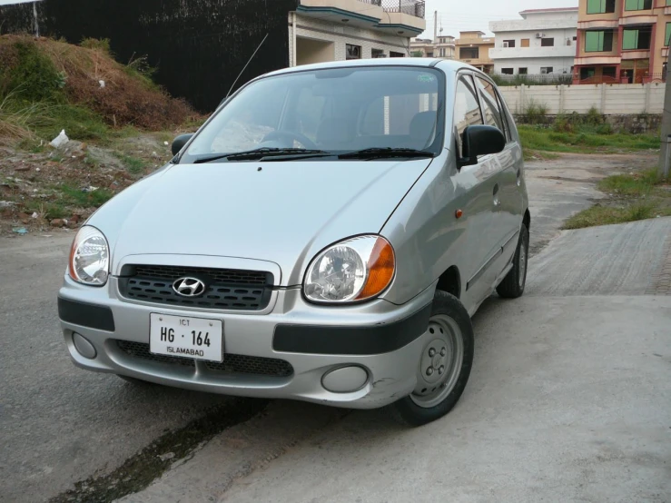 small silver van parked on pavement next to buildings