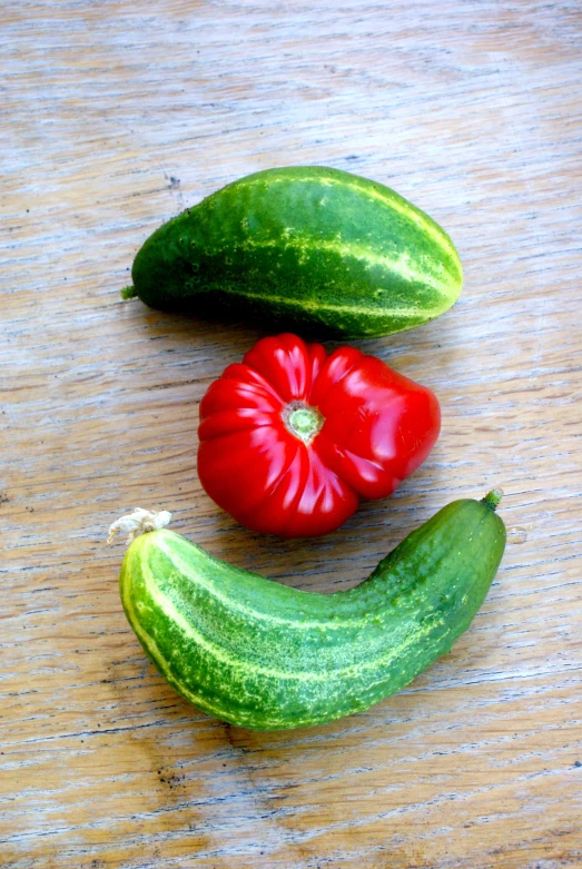 two red peppers and three green bananas on a wood table