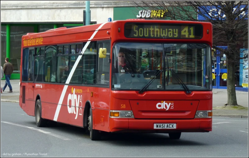 a red city bus in the middle of an intersection
