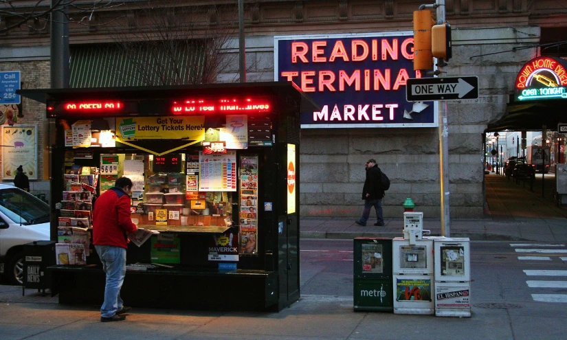 a man standing at an electric newspaper vending machine