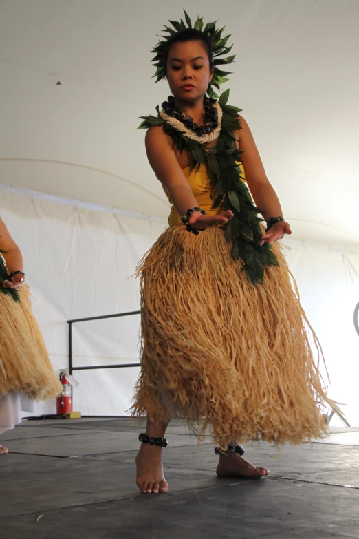 young woman in grass skirt standing in front of white backdrop