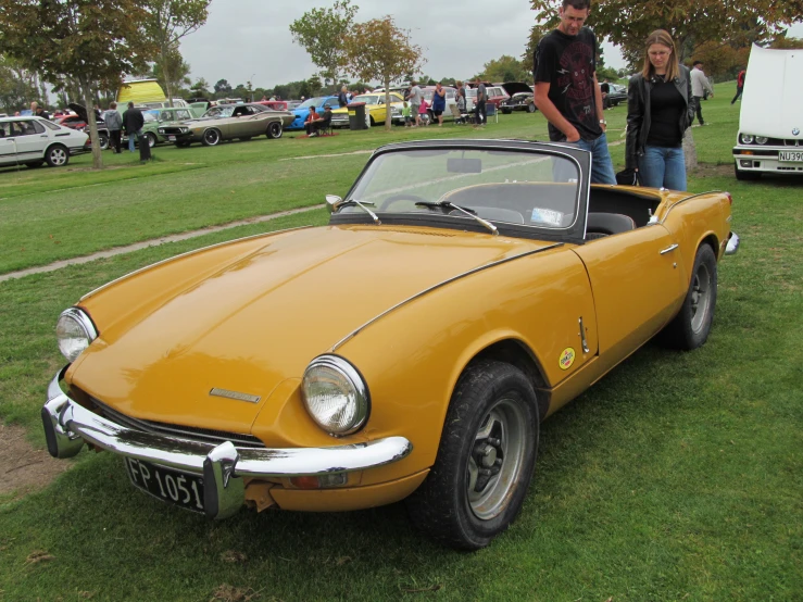 there is an old yellow car parked on grass