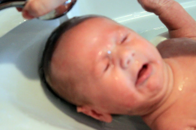 baby sitting in a sink with his mouth open