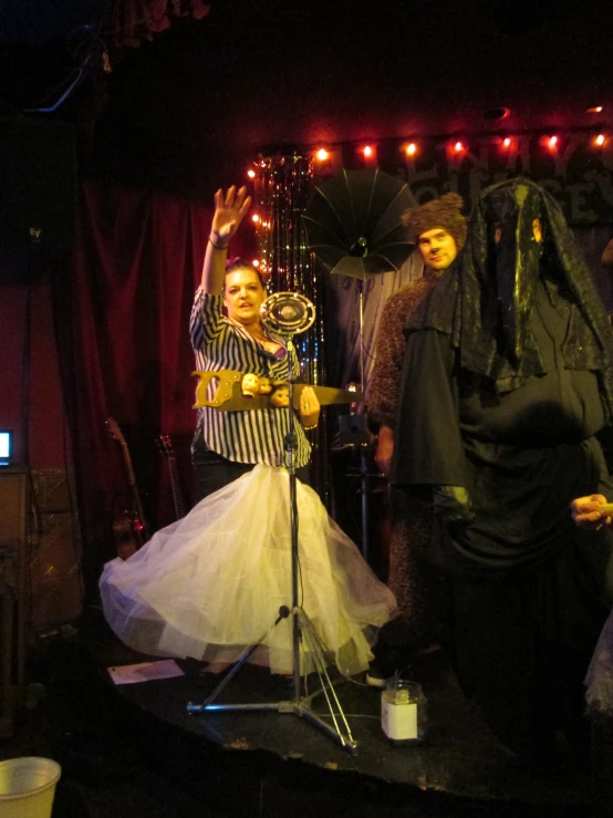 a person with an umbrella on stage near other performers