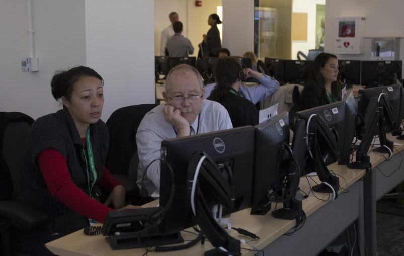 two people at computers on desks working together