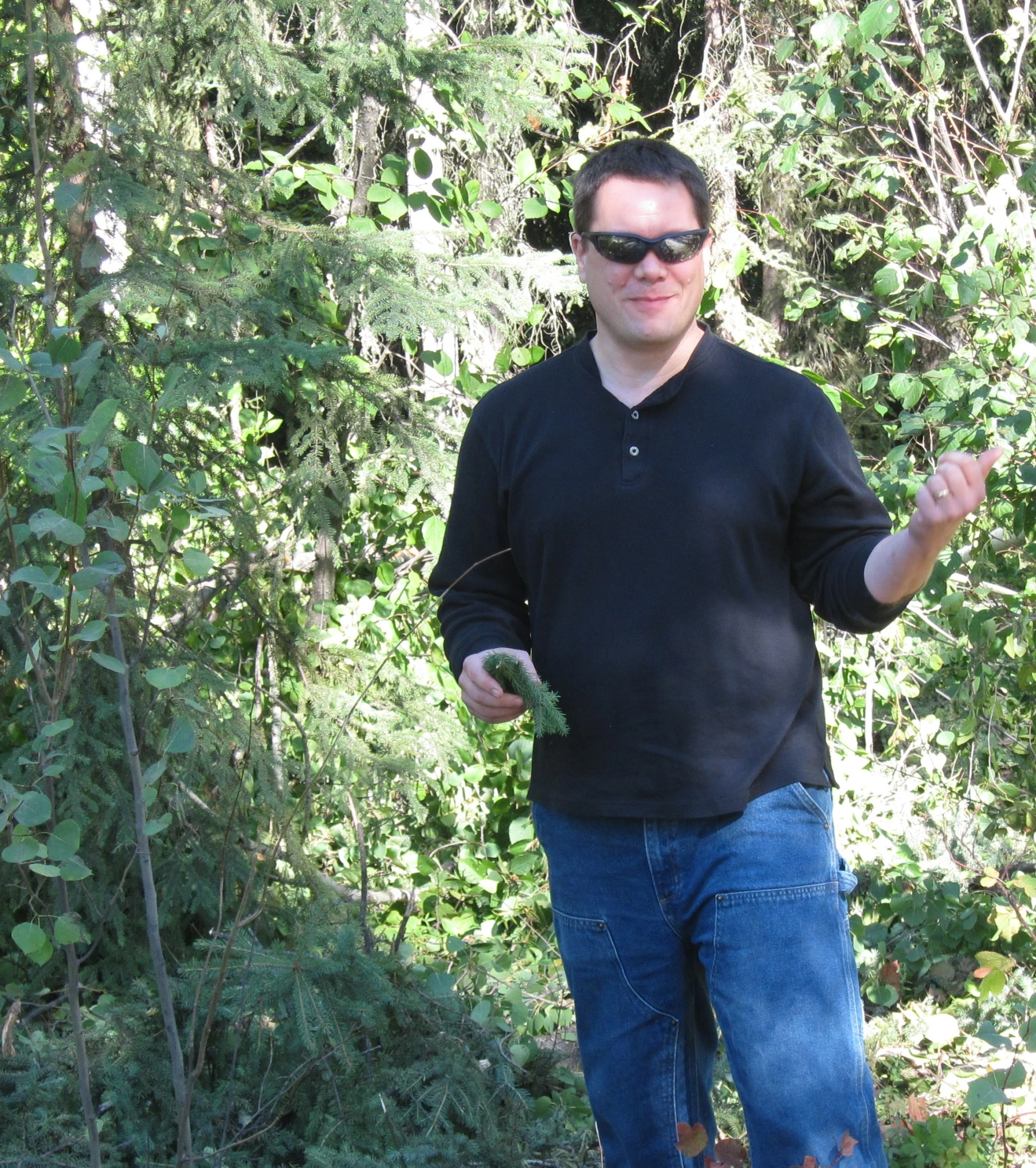 the man stands outside by some trees holding soing in his hands